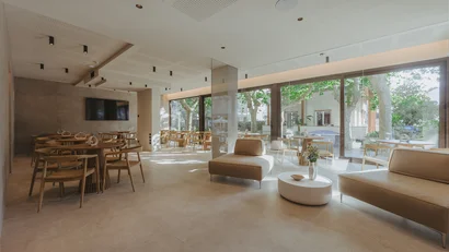 Sala luminosa con tavoli in legno e grandi finestre con vista sul giardino