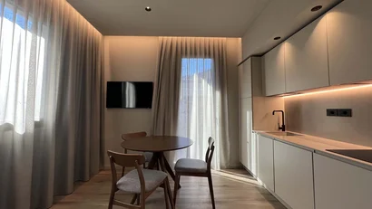 Cucina moderna con tavolo rotondo e tre sedie vicino a finestra con tende