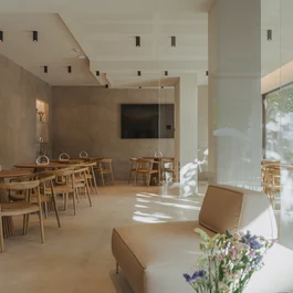Sala da pranzo moderna con tavoli in legno e sedie in un ambiente luminoso