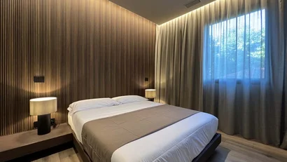 Camera da letto moderna con letto matrimoniale, illuminazione soffusa e tende beige.