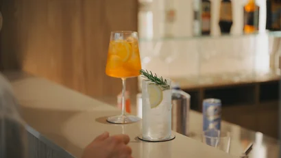 Due cocktail sul bancone di un bar con bottiglie sullo sfondo