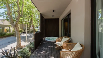 Balcone con due poltrone in vimini e vasca idromassaggio con vista su strada alberata