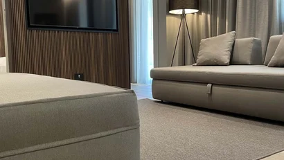 Soggiorno moderno con divano beige, TV a parete e lampada da terra