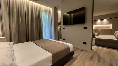 Camera da letto moderna con letto matrimoniale e TV a parete