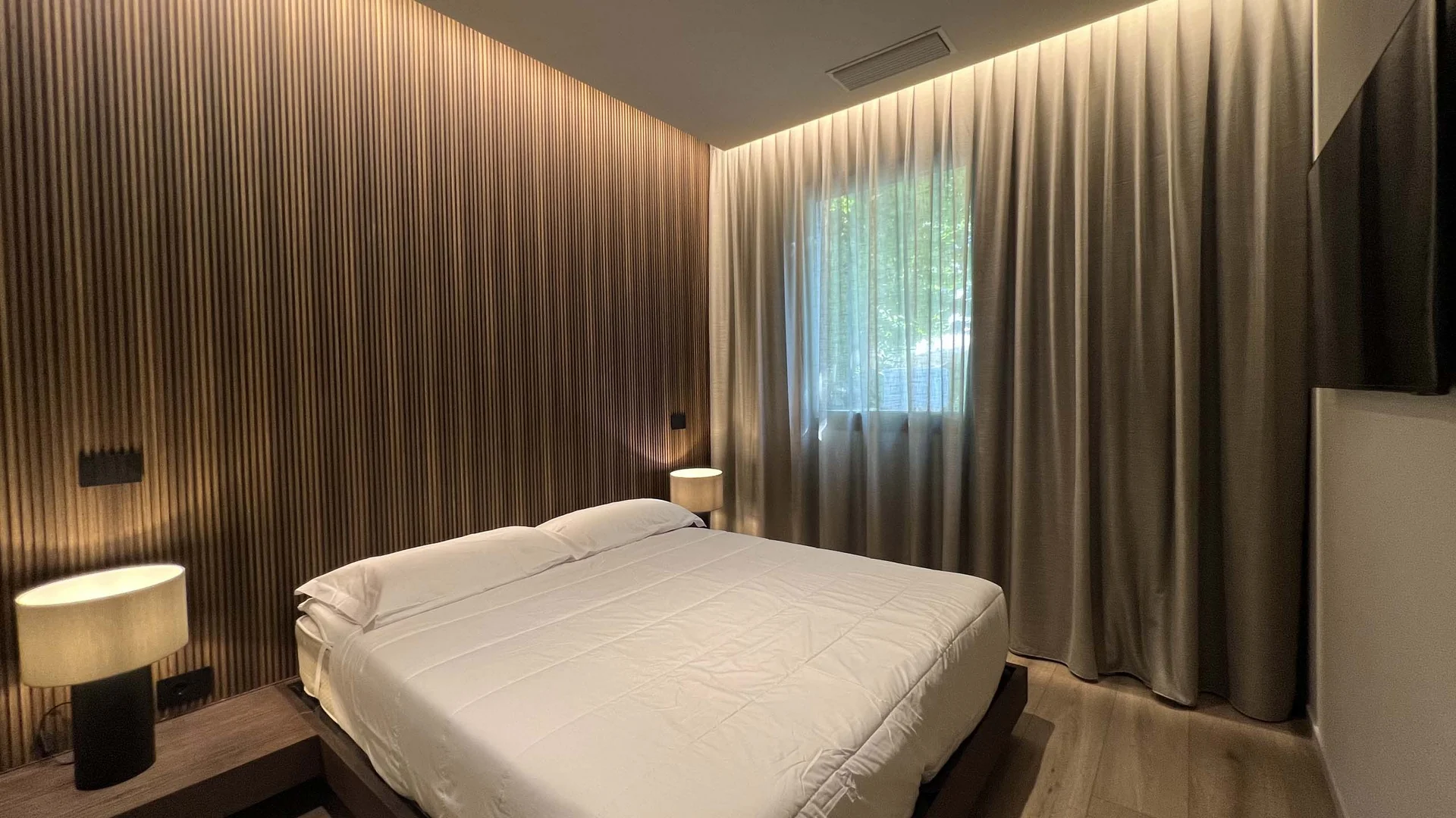 Camera da letto moderna con parete in legno e luce soffusa