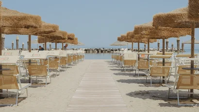 Ombrelloni di paglia e sedie a sdraio ordinate su una spiaggia sabbiosa