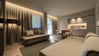 Soggiorno moderno con divani beige e cucina minimalista illuminata