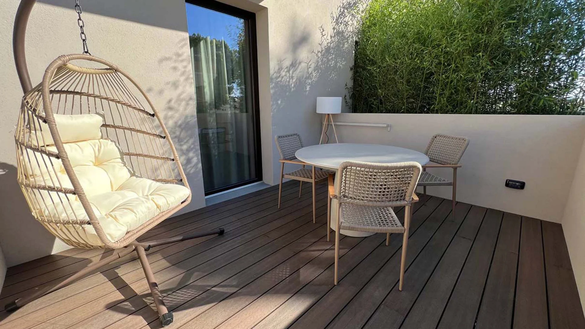 Terrazza con sedia sospesa e tavolo rotondo con tre sedie