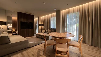 Soggiorno moderno con divani beige, tavolo rotondo e sedie in legno chiaro