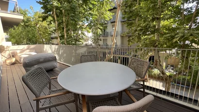 Terrazza con tavolo rotondo, quattro sedie e alberi verdi intorno