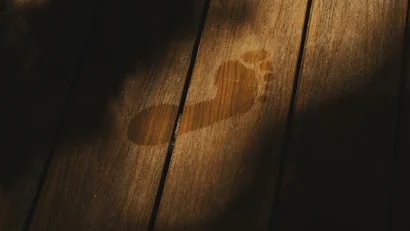 Impronta di piede bagnato su pavimento in legno illuminato dal sole