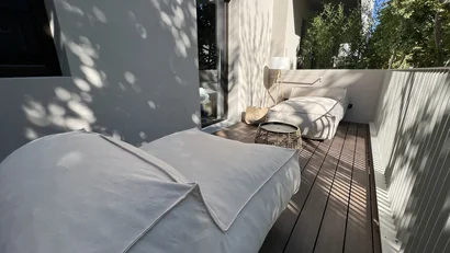 Terrazza con due lettini imbottiti bianchi e tavolino su pavimento in legno