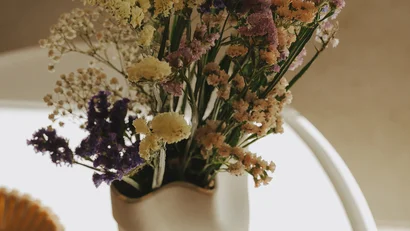 Vaso bianco con fiori secchi colorati su tavolo rotondo bianco