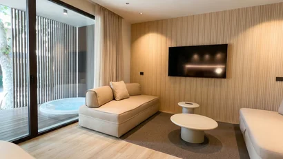 Salotto moderno con divani beige, tv a parete e vasca idromassaggio