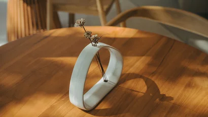 Vaso bianco moderno con fiori secchi su tavolo di legno