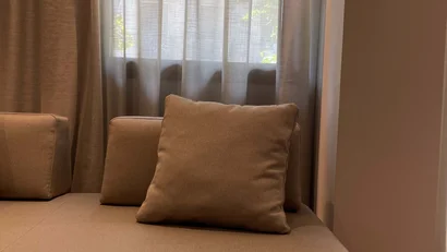 Divano moderno beige con cuscino davanti a una finestra con tende leggere