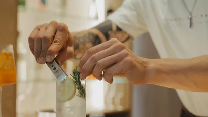 Barista prepara un cocktail con fetta di limone e ramo di rosmarino