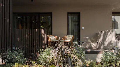 Terrazza con due sedie in vimini e tavolino, piante verdi in primo piano