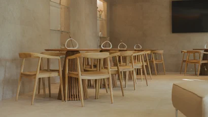 Sala moderna con tavoli e sedie di legno chiaro e pareti beige
