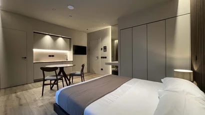 Camera da letto moderna con letto, tavolo, sedie e angolo cucina minimalista